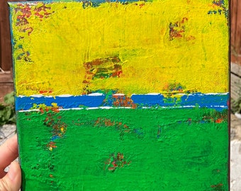 May include: Abstract painting on canvas with a yellow top section, a blue and white stripe, and a green bottom section. The painting has a textured, layered look.