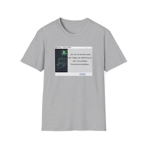 Peut inclure: T-shirt gris clair avec un motif sur le thème de l'ordinateur. Le motif comprend une icône d'ordinateur et le texte en français : "Je ne prends pas de l'âge, je débloque de nouvelles fonctionnalités."