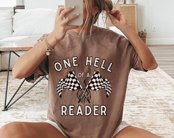 May include: A brown t-shirt with the text "One Hell of a Reader" and a graphic of two chequered flags crossed with flames.