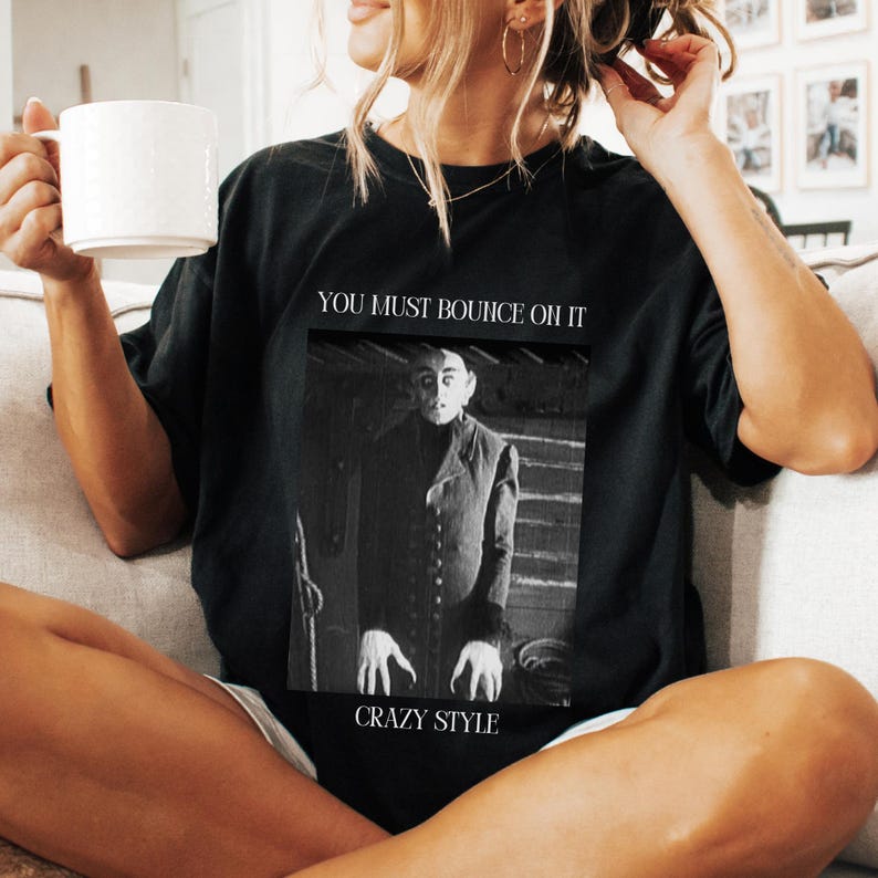 May include: Black t-shirt with a graphic print of a man in a black suit with the text "You must bounce oh it Crazy Style".