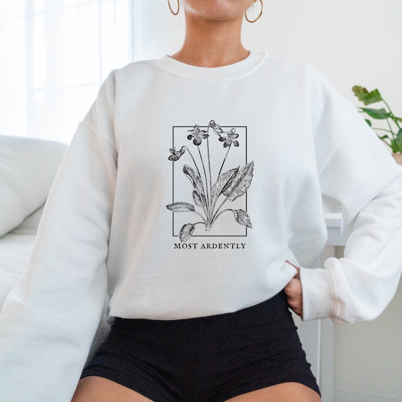 May include: White sweatshirt with a black and white illustration of a flower with the text "MOST ARDENTLY" printed below.