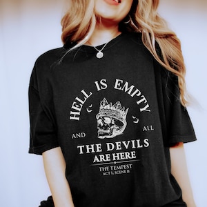 May include: Black t-shirt with a white graphic print of a skull wearing a crown. The text reads "Hell is empty and all the devils are here."  The text "The Tempest Act I, Scene II" is also printed on the shirt.