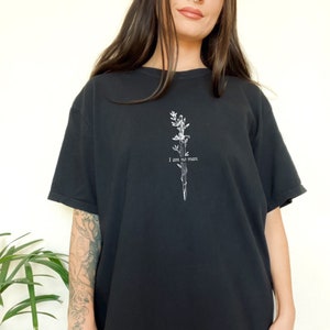 Pode incluir: Camiseta preta com um gr&aacute;fico branco de uma espada com videiras e o texto "I am no man".