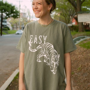 May include: A green t-shirt with a white tiger graphic and the word "EASY" printed on the front.