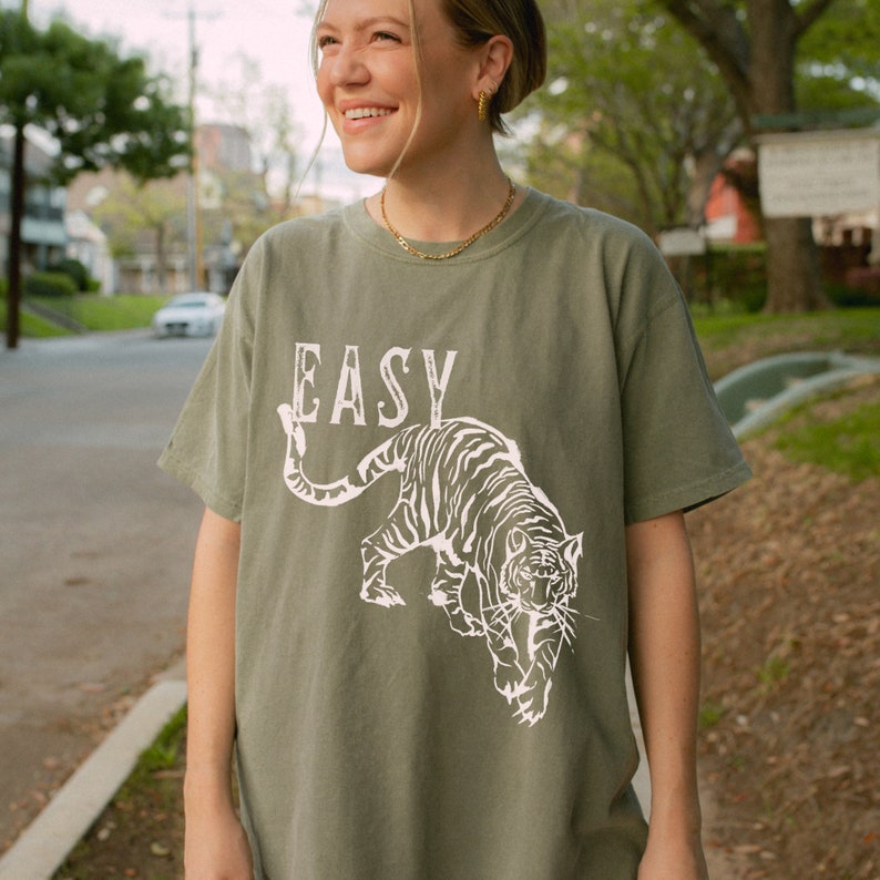 May include: A green t-shirt with a white tiger graphic and the word "EASY" printed on the front.