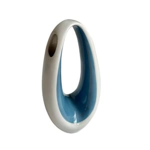 May include: A white and blue ceramic vase with a unique, open teardrop design. The interior is a vibrant blue, contrasting with the white exterior. The vase has a smooth, glossy finish and a small opening at the top.