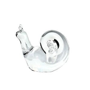 May include: A clear glass snail sculpture with a curled shell. The snail is a decorative object.
