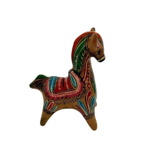 May include: A hand-painted wooden horse figurine with intricate details. The horse is brown with green, red, and blue accents. The horse is standing on all four legs and has a saddle.