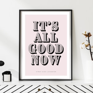 Puede incluir: Una impresión tipográfica en blanco y negro con el texto "IT'S ALL GOOD NOW" sobre un fondo rosa claro. El texto está en una fuente en negrita de estilo 3D. La parte inferior de la impresión dice "Stray Kids Levanter".