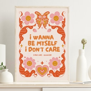 Puede incluir: Una impresión artística enmarcada con un diseño retro. La obra presenta el texto "i wanna BE MYSELF i DON'T CARE" en naranja, rodeado de flores rosas, una mariposa y remolinos decorativos naranjas. También se incluye el texto "Stray Kids - Levanter".