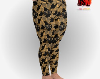 Puede incluir: Leggings negros con un patrón repetido de mariposas doradas. Los leggings son ajustados y de cintura alta. La imagen también incluye el logotipo de "FSW Tee Company".