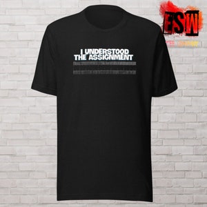 May include: Black t-shirt with white text that reads "I understood the assignment" and a ruler graphic below the text.