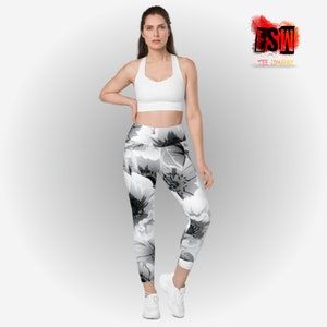 May include: A woman wearing a white sports bra and black and white floral leggings. The leggings feature a large floral pattern in shades of gray and white. The logo "FSW TEE COMPANY" is in the upper right corner.