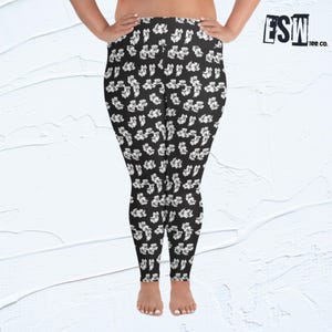 May include: Black leggings with a white floral pattern. The leggings are shown on a model and have a waistband.