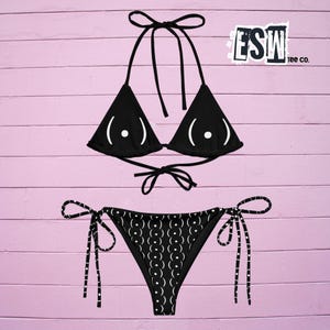 Puede incluir: Bikini negro con un estampado gráfico blanco de un par de ojos en la parte superior y un patrón repetitivo de ojos en la parte inferior. El bikini está fotografiado sobre un fondo rosa. El texto "FSW tee co." es visible en la esquina superior derecha de la imagen.