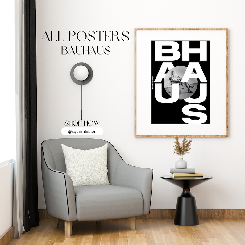 May include: A black and white poster with the text "BAHAUS" in bold white letters. The letters are arranged in a circle with a person sitting in a chair in the center of the circle. The poster is framed in a light wood frame and is hanging on a white wall.