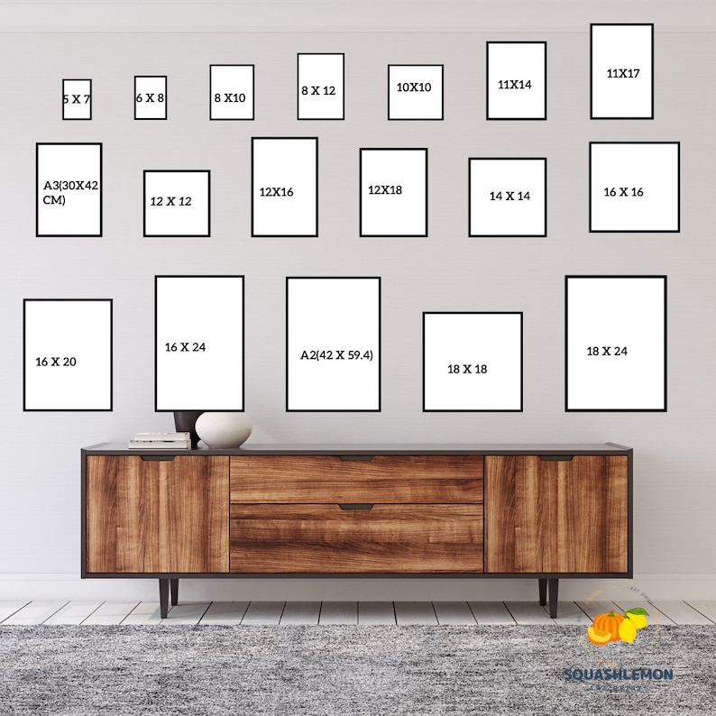 May include: A white wall with a variety of black picture frames of different sizes. The frames are arranged in a grid pattern. The frames are all empty. A wooden dresser is in front of the frames. The dresser has two drawers and a brown top. The dresser is sitting on a gray rug.
