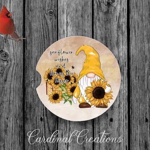 May include: A yellow gnome with a white beard and a red hat is holding a sunflower. The gnome is surrounded by sunflowers and the text "sunflower wishes and Honey Bee Kisses".