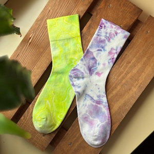 May include: Two pairs of tie-dye socks, one in a yellow and green swirl pattern and the other in a purple and white swirl pattern.
