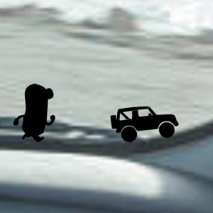 May include: A black silhouette of a cartoon character walking next to a black silhouette of a jeep on a blurry background.