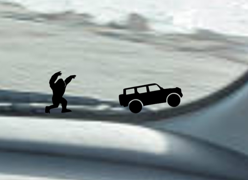 May include: A black silhouette of a Bigfoot or Sasquatch walking towards a black silhouette of a car. The image is on a white background.