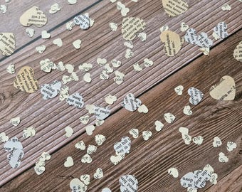 May include: A collection of small, heart-shaped confetti pieces cut from vintage book pages. Each heart features printed black text on off-white or beige paper, showcasing various words and sentence fragments from the original literary source material.