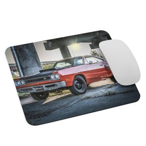 May include: A red 1969 Dodge Charger with black racing stripes and a black hood. The car is parked under a bridge with a sun shining through the beams.