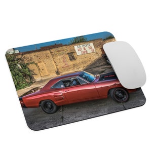 May include: A red 1969 Dodge Super Bee muscle car parked in front of a brick building with a sign that reads "Complete Automotive Shop".