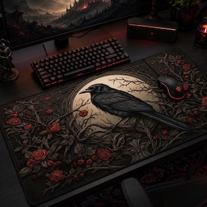 May include: A rectangular desk mat featuring a central circular emblem with a black raven perched on gnarled branches. The design includes dark, intricate vines and deep red roses against a black background, with a black computer mouse resting on top.