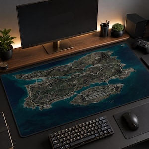 May include: A large rectangular desk mat featuring a detailed satellite-style map of an island surrounded by deep blue ocean water. The map displays various terrain features, white road networks, and labeled locations across the landmass.