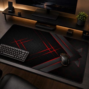 Può includere: Un tappetino da scrivania rettangolare con sfondo nero, un sottile motivo esagonale e audaci linee rosse che si intersecano. Il tappetino ha una superficie liscia con un bordo nero, offrendo un'ampia area per una tastiera e un mouse neri.