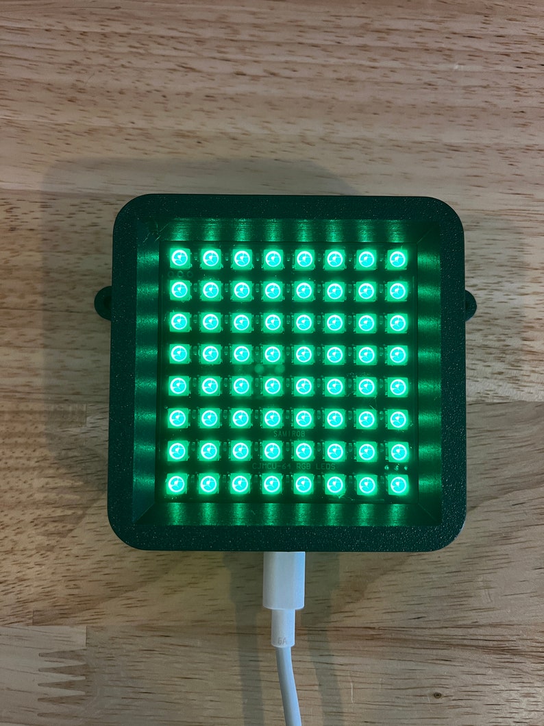 May include: A green rectangular box with a grid of 64 small green LED lights. The box is connected to a white USB cable. The text "SAM700" and "CYMCU-64 RGB LEDs" is printed on the box.