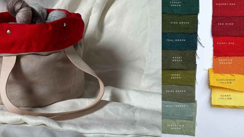 May include: A beige linen tote bag with a red fabric lining and two cream-colored handles. The bag is filled with yarn balls in various shades of blue and gray. The image also shows a color chart with swatches of different shades of green and red.