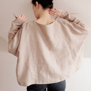 Cozy yet stylish linen kimono top in a warm beige hue. Featuring flowy batwing sleeves and delicate wrist ties, this relaxed-fit blouse is perfect for layering or wearing on its own