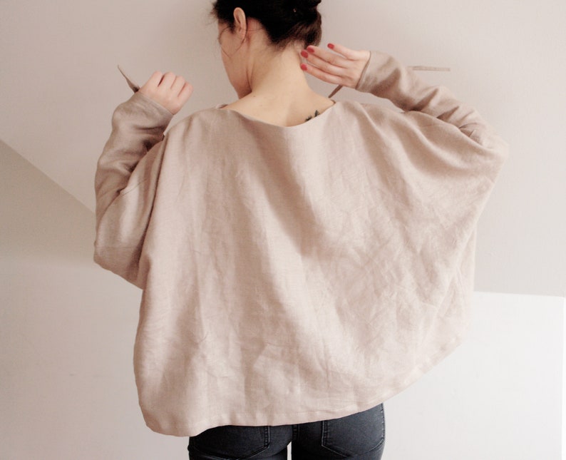Cozy yet stylish linen kimono top in a warm beige hue. Featuring flowy batwing sleeves and delicate wrist ties, this relaxed-fit blouse is perfect for layering or wearing on its own