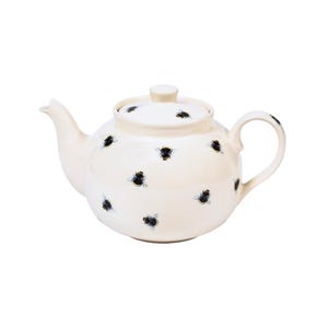 Op de afbeelding: Crèmekleurige keramische theepot met deksel, versierd met zwarte en blauwe bijenmotieven. De theepot heeft een gebogen tuit en een afgeronde handgreep. Het deksel heeft een kleine knop voor eenvoudige verwijdering.