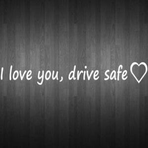 May include: White text on a dark gray wooden background reads "I love you, drive safe" with a heart symbol. The message is a simple expression of affection and care, suitable for a gift or a personal message.