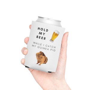 May include: White can cooler with the text "Hold My Beer While I Catch My Guinea Pig" and a picture of a guinea pig and a glass of beer.
