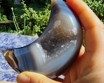 Tallado de media luna en ágata azul parcialmente pulido a mano con bolsillo de geoda drusa, soporte de exhibición incluido. 190 g.