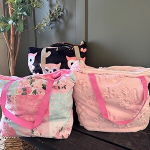 Peut inclure: Trois sacs fourre-tout de différents modèles. L'un est noir avec des motifs de hiboux, un autre est rose clair avec des motifs floraux, et le troisième est rose texturé avec des poignées roses. Tous les sacs ont des poignées roses.