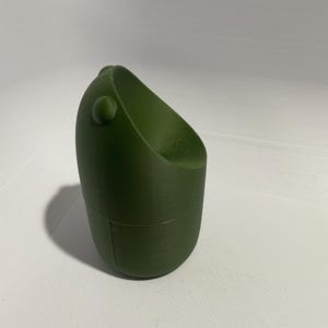 Puede incluir: Un contenedor cilíndrico verde impreso en 3D con una parte superior redondeada y una pequeña perilla redonda en el lateral.