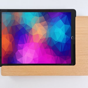 May include: A tablet computer with a colorful geometric pattern on the screen is resting on a wooden stand.