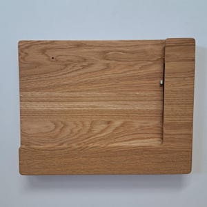Könnte beinhalten: Ein Schneidebrett aus Holz mit einem eingebauten Seitenregal. Das Brett ist aus hellbraunem Holz mit einer natürlichen Maserung.