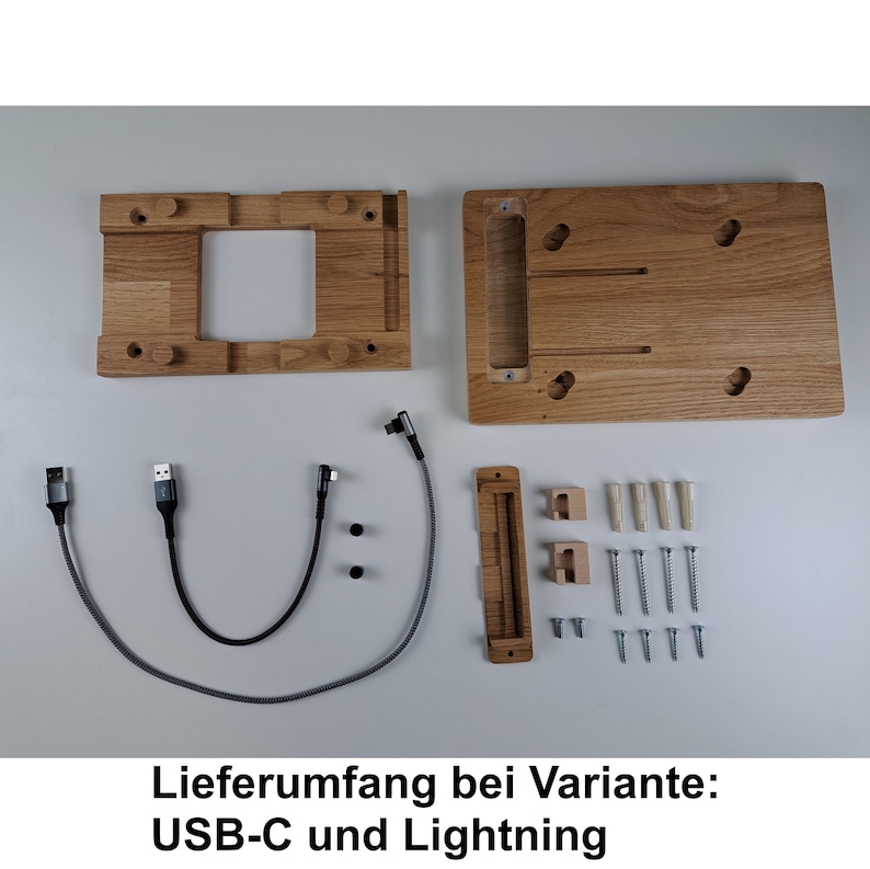 May include: A wooden phone stand with a cutout for a phone and a cable management system. The stand comes with two cables, screws, and mounting hardware. The text "Lieferumfang bei Variante: USB-C und Lightning" is visible in the image.