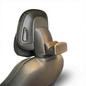 K&ouml;nnte beinhalten: Eine schwarze Kopfst&uuml;tze f&uuml;r einen Autositz mit integrierter Armlehne. Die Kopfst&uuml;tze hat einen rechteckigen Knopf und einen gen&auml;hten Rand. Die Armlehne ist hellgrau und ragt nach au&szlig;en. Der Sitz besteht aus einem glatten, dunklen Material.