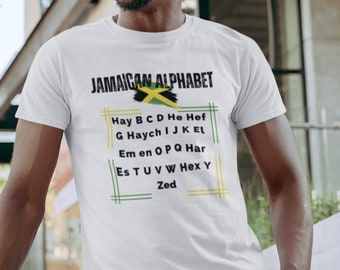 Può includere: Una maglietta bianca con una grafica della bandiera giamaicana e il testo "JAMAICAN ALPHABET" stampato sul davanti. Il testo elenca le lettere dell'alfabeto in patois giamaicano.