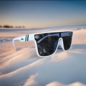May include: White sunglasses with dark lenses. The sunglasses feature a thick white frame with black stripes on the arms and a logo. They are set against a snowy backdrop.