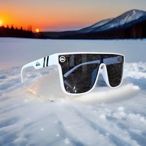 May include: White sunglasses with a wide frame and dark lenses. The sunglasses have a logo on the temple and a black stripe. The background shows a snowy landscape with a sunset.