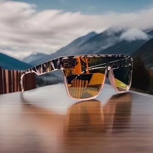 K&ouml;nnte beinhalten: Sonnenbrille mit flachem Rahmenoberteil und einem schwarz-wei&szlig;en Tiermuster auf den B&uuml;geln und der Vorderseite. Die Gl&auml;ser sind reflektierend mit einem warmen Orange- und Gelbstich und zeigen eine Spiegelung einer Holzstruktur.