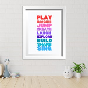 May include: A white framed print with the words "PLAY", "IMAGINE", "JUMP", "CREATE", "LAUGH", "EXPLORE", "BUILD", "SHARE", and "SING" in a rainbow gradient.